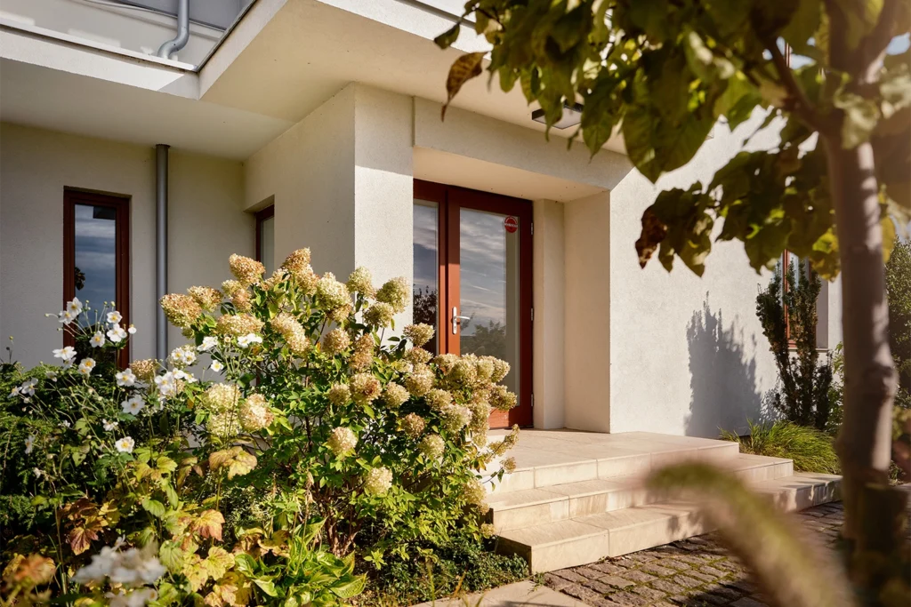 Wejście do domu z tarasem i roślinnością wokół budynku