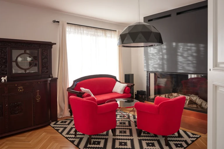 Salon z czerwonymi fotelami i kominkiem – fotografia wnętrz Koszalin