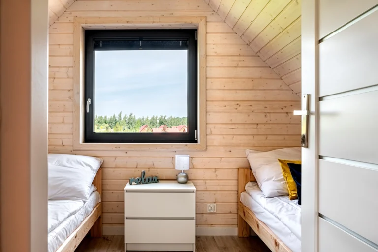 Sypialnia z łóżkiem i oknem w drewnianej zabudowie